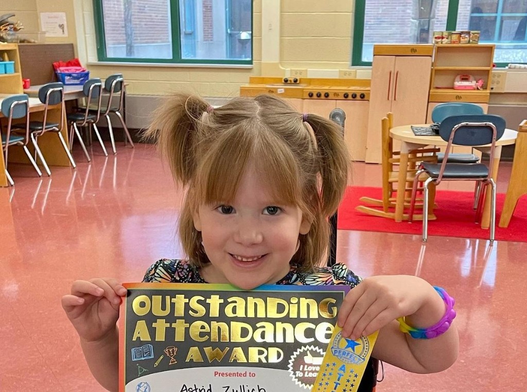 Astrid smiling and holding her Outstanding Attendance Award